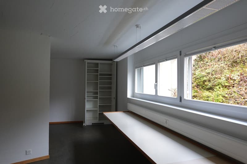 Completely empty room with white walls, black floor, a white shelf, and a bench under the window.