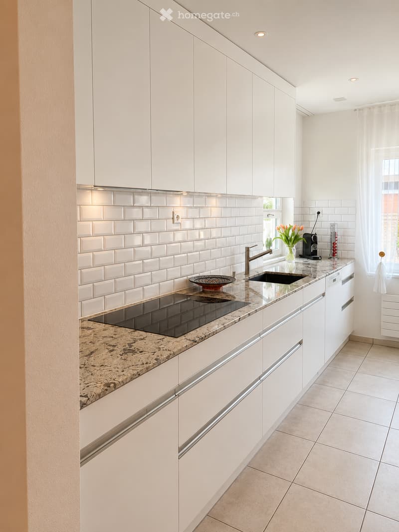 Modern kitchen with white cabinets, granite countertop, stainless steel sink, and built-in appliances.