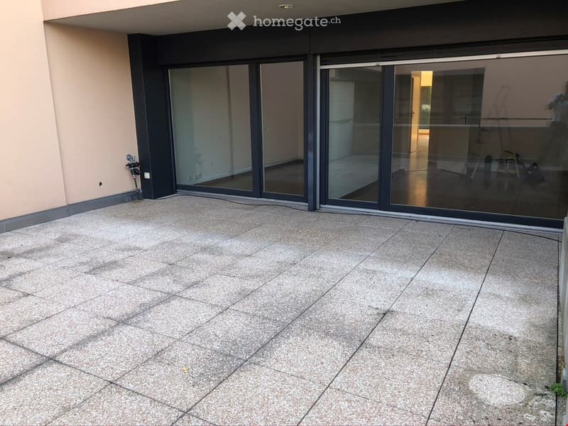 Empty balcony with large sliding glass doors leading to an interior space, tiled floor, and modern design.