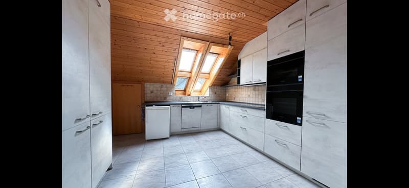 Modern kitchen with white cabinets, stainless steel appliances, and skylight windows.