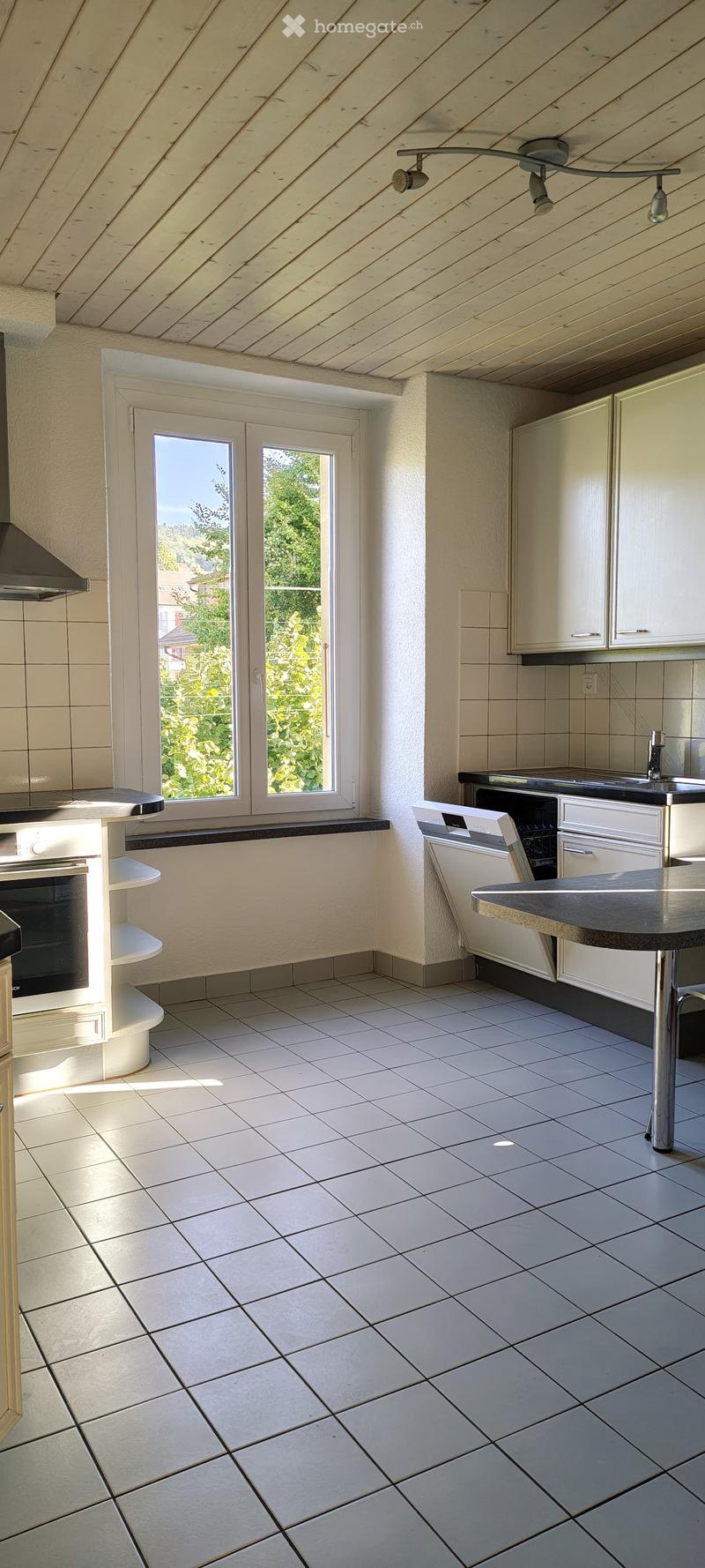 Modern kitchen with white tiled floor, white cabinets, stainless steel appliances, and a central island with a sink and dishwasher.