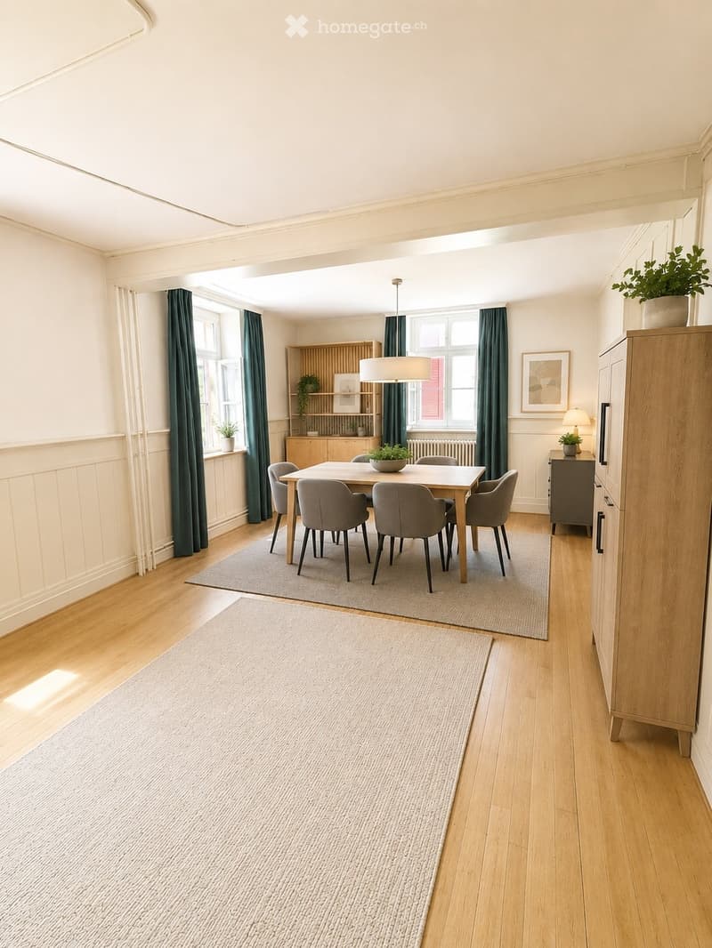 Bright dining area with wooden flooring, a central dining table surrounded by six chairs, a modern pendant light, and a built-in wooden cabinet with shelves and a lamp on top. Two rugs are placed on the floor, and there are potted plants and framed artwor