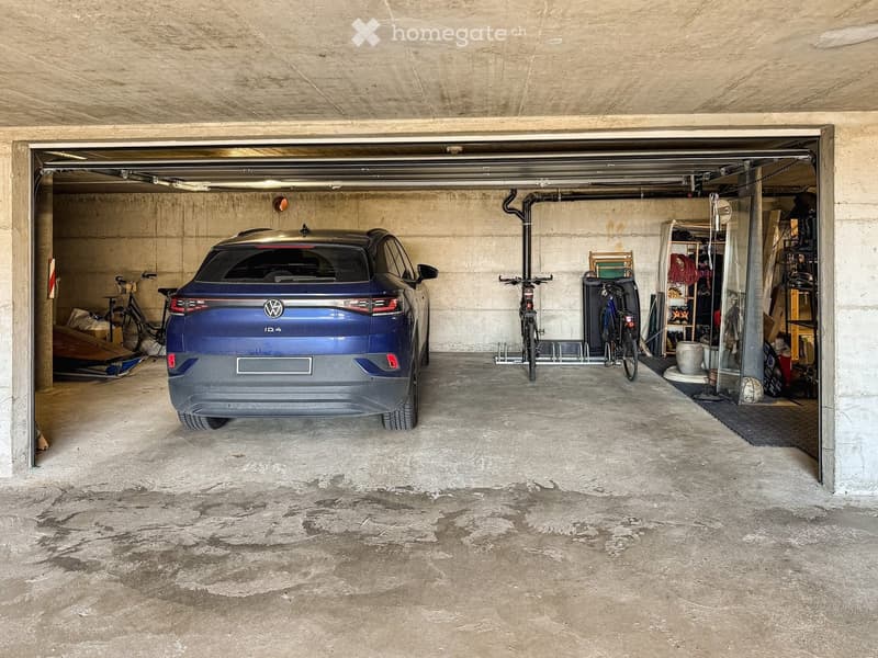Underground garage with a blue Volkswagen ID.4, bicycles, and storage shelves.
