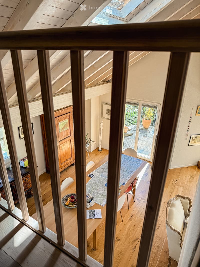 A well-lit room with wooden floors, a dining table with chairs, a sofa, a cabinet, and a view to a balcony area with outdoor furniture.
