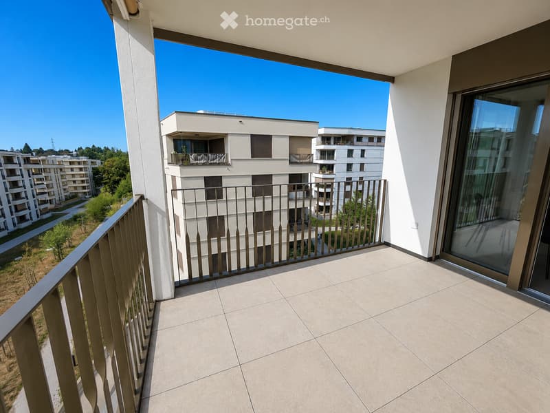 Balcony with tiled floor, metal railing, and a view of modern apartment buildings and greenery.
