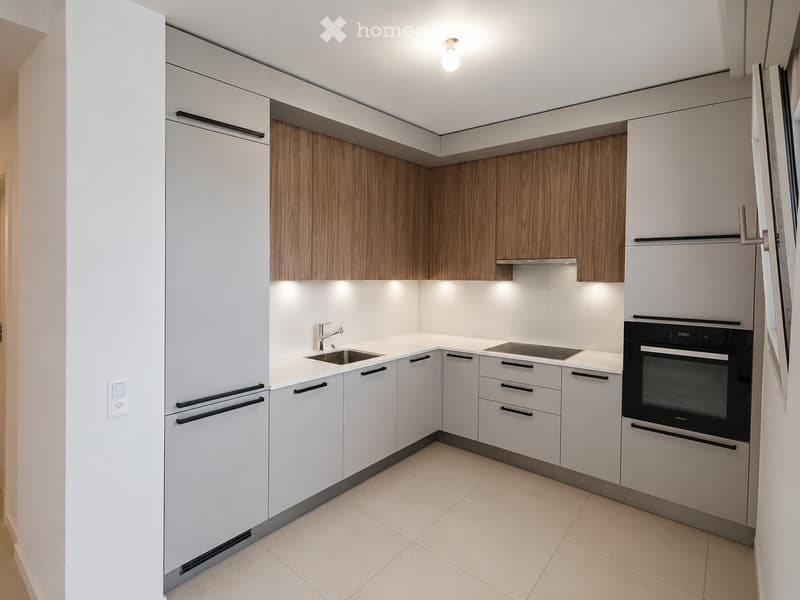 Modern kitchen with white cabinets, wooden accents, a sink, faucet, and built-in oven.