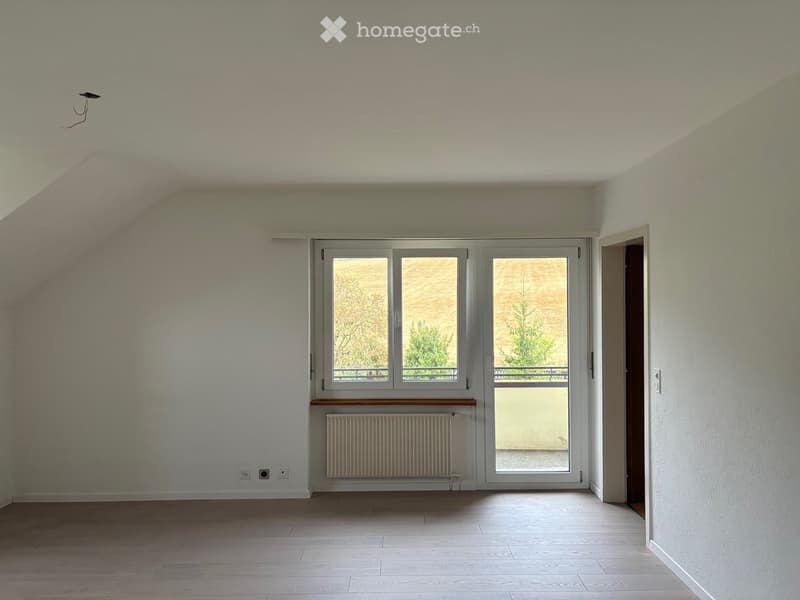 Empty room with wooden flooring, white walls, large window with view, radiator, and open doorway leading to another space.