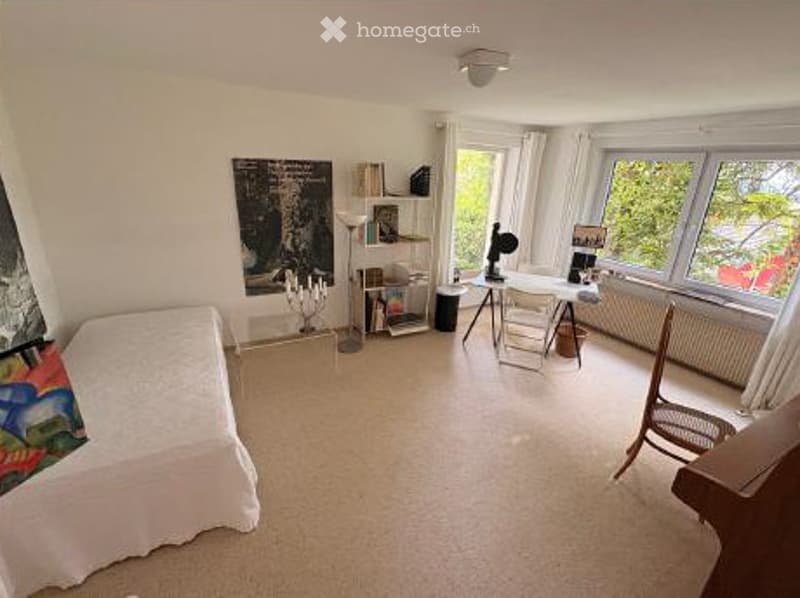 A well-lit room with a bed, a chair, a table, a shelf, a lamp, and a picture frame on the wall.