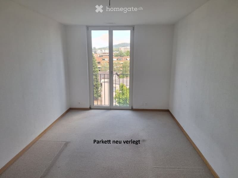Empty room with light-colored walls, carpeted floor, and large sliding glass door leading to a balcony.