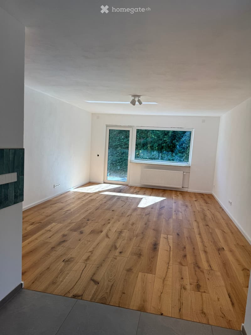Empty room with wooden flooring, white walls, large windows, and a radiator. No furniture or equipment present.