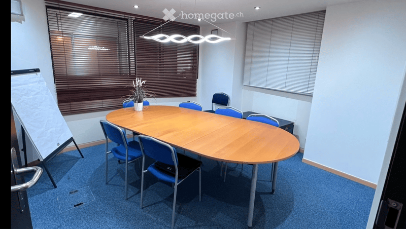oval conference table, blue chairs, wooden floor, white walls, windows, whiteboard