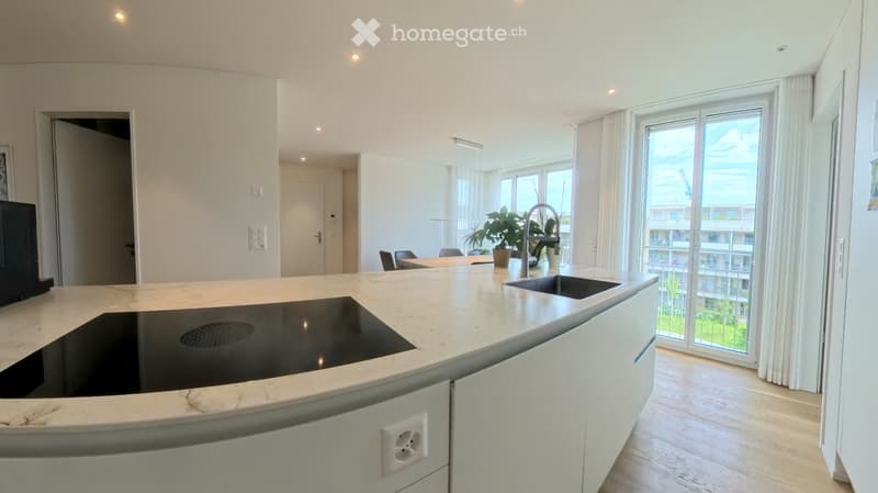 Modern kitchen with white cabinets, marble countertop, induction cooktop, sink, and large windows with a view of the city.