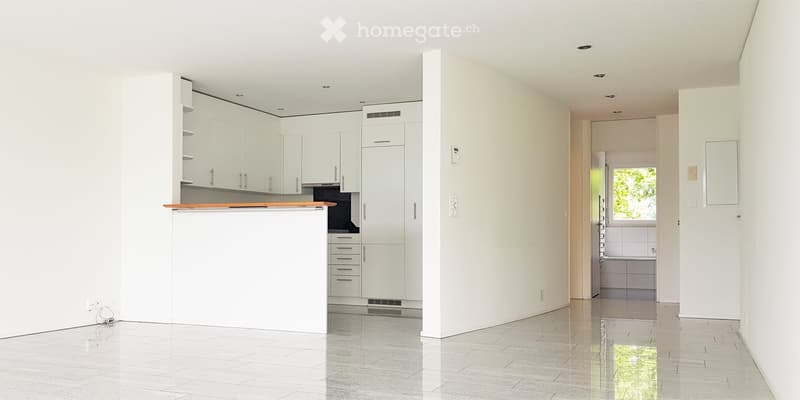 Modern, minimalist kitchen with white cabinets, a wooden countertop, and a tiled floor. The space is clean and uncluttered, with no visible furniture or appliances.