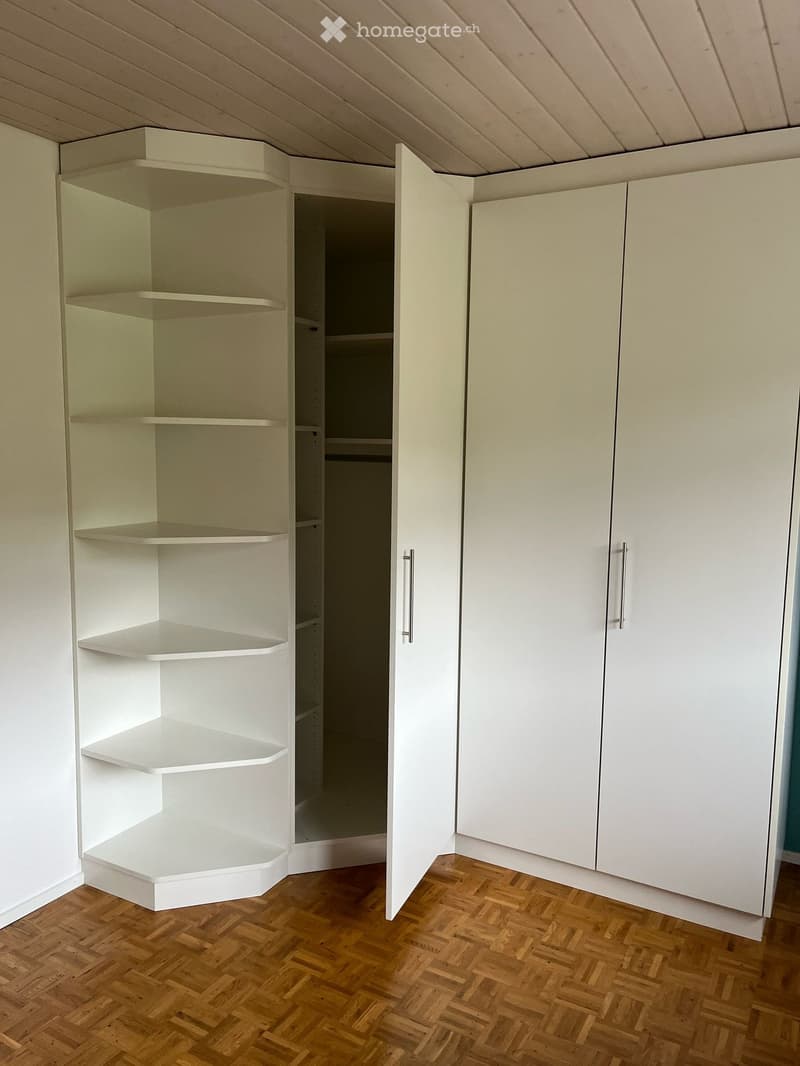 Large corner wardrobe with shelves and double doors. Wood floor.