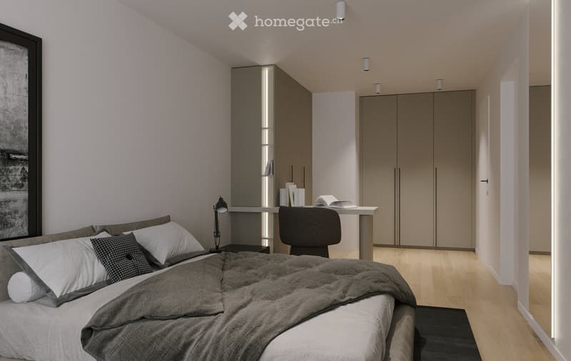 Modern bedroom with a large bed, pillows, and a blanket, a sleek wardrobe, a desk with a chair, and a lamp. The room features light wooden flooring and built-in storage.