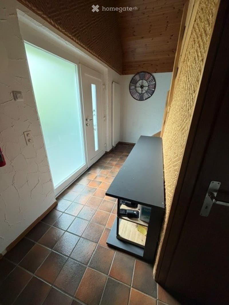 Hallway with wooden ceiling, tiled floor, bench, and wall clock.
