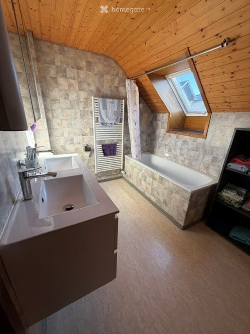Bathroom with double sink, bathtub, radiator, and a skylight window above the tub.