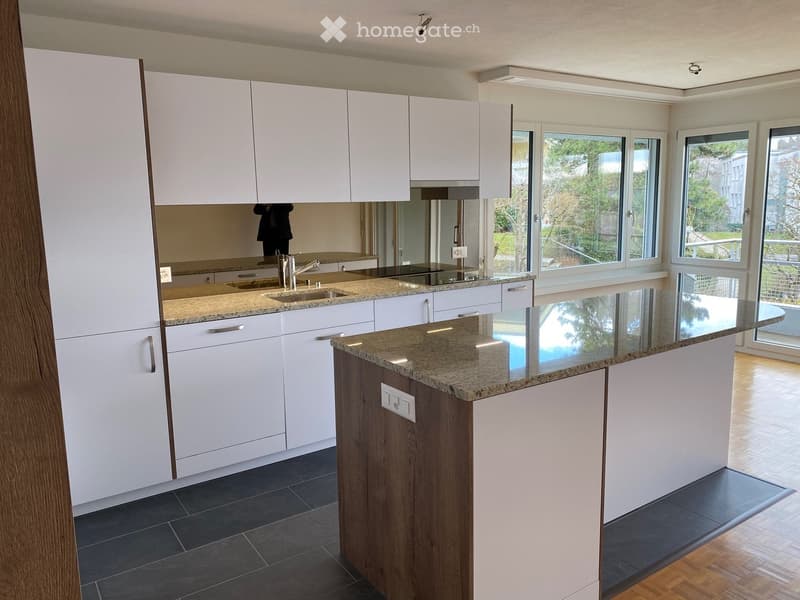 Modern kitchen with white cabinets, granite countertops, and a central island. Features a sink with a modern faucet and ample storage space.
