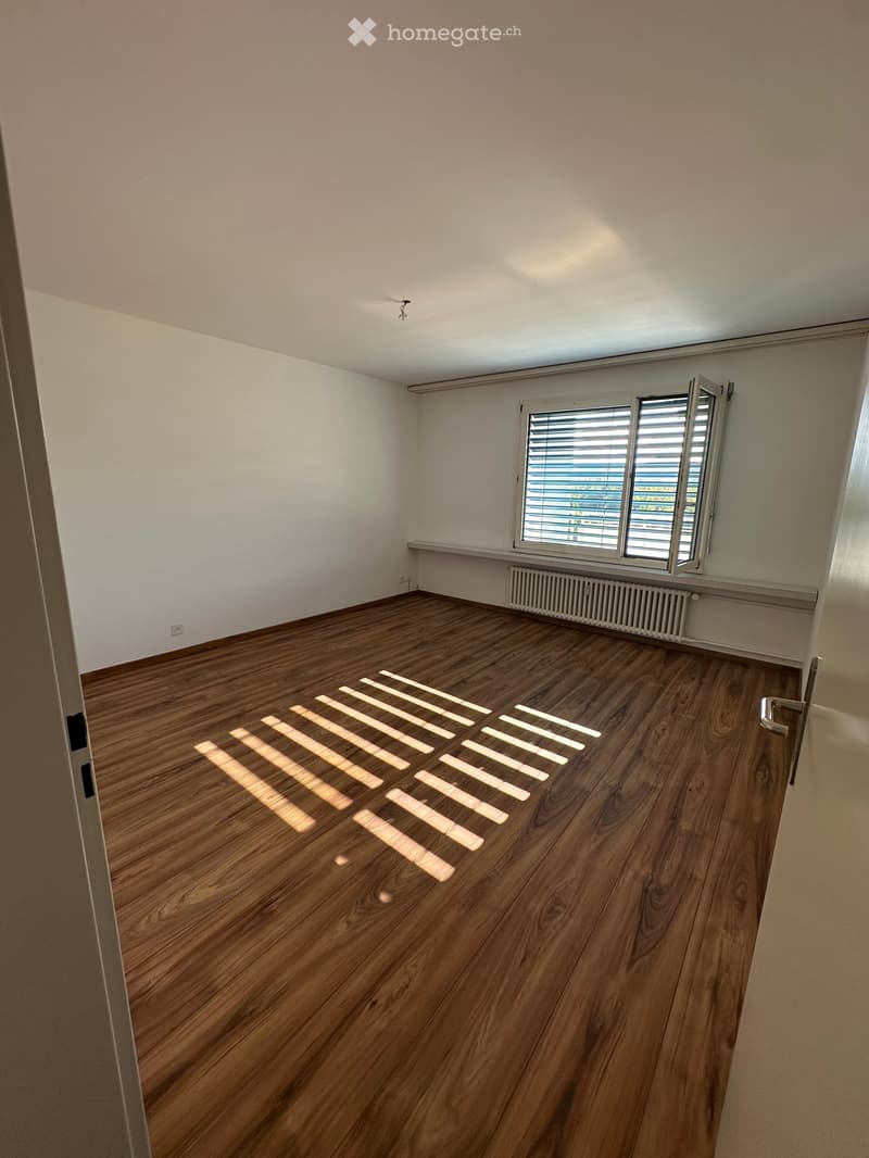 Empty room with wooden flooring, white walls, and a window with blinds. No furniture or equipment present.