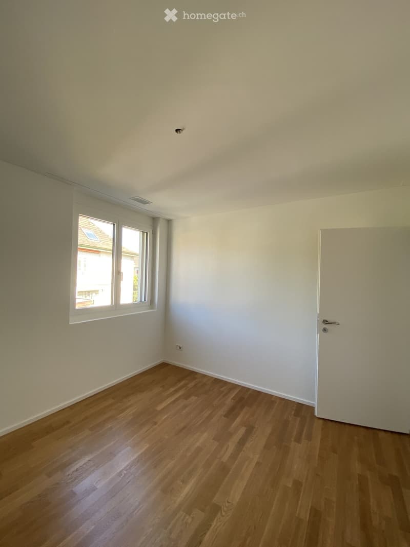 Empty room with light-colored walls, wooden flooring, and a single window with white frame. No furniture or equipment present.