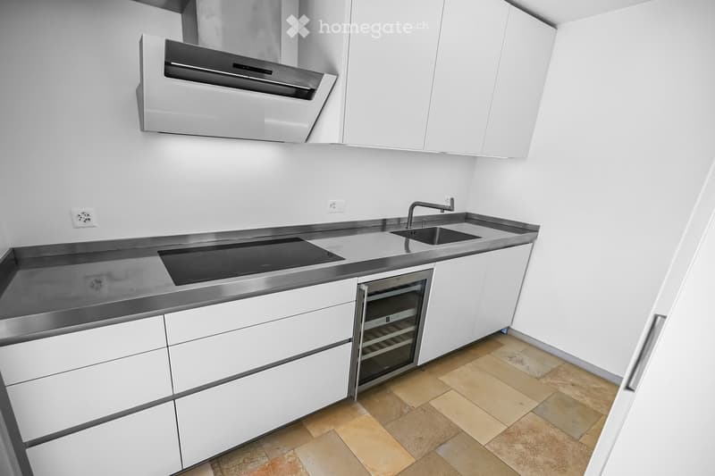 Modern kitchen with white cabinets, stainless steel appliances, induction cooktop, sink, and wine cooler.