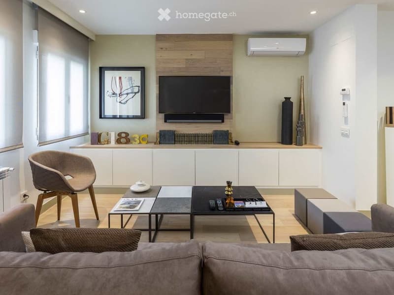 Modern living room with a grey sofa, wooden coffee table, TV mounted on a wooden wall, and decorative vases.