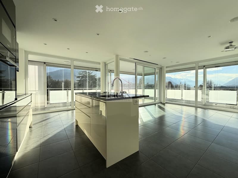 Modern kitchen with a central island, sleek countertops, and expansive windows offering a scenic mountain view.