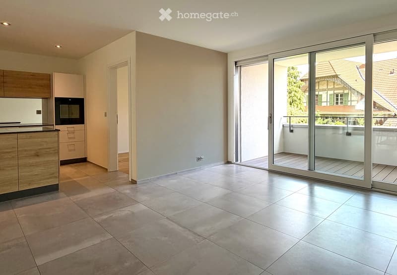 Empty kitchen with tiled floor, wooden cabinets, and a sliding glass door leading to a balcony.