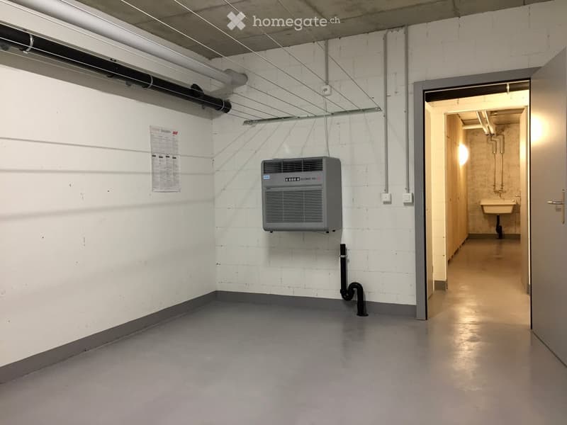Empty room with white brick walls, grey floor, air conditioning unit, and a doorway leading to another room with a sink.
