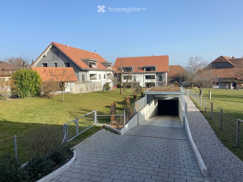Residential complex with modern houses, red-tiled roofs, and a paved pathway leading to a garage entrance.