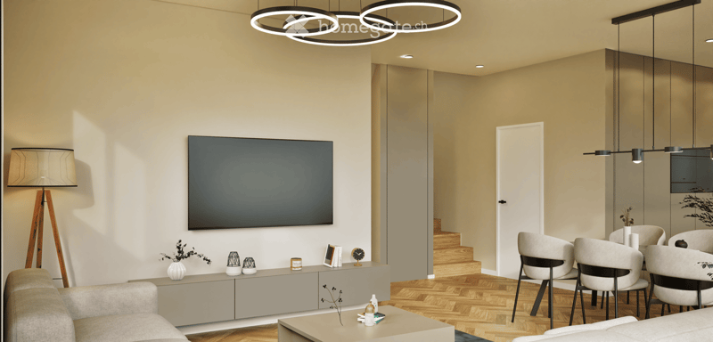 Modern living room with a grey sofa, coffee table, large flat-screen TV, floor lamp, and a dining area with chairs and a table. The room features wooden flooring and contemporary decor.