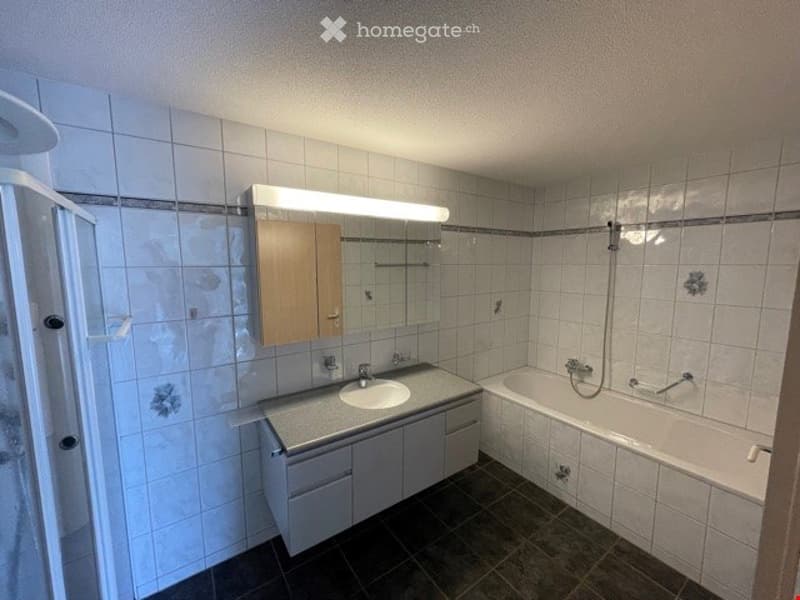 Modern bathroom with white tiled walls, a sink with a mirror, a bathtub, and a cabinet under the sink.