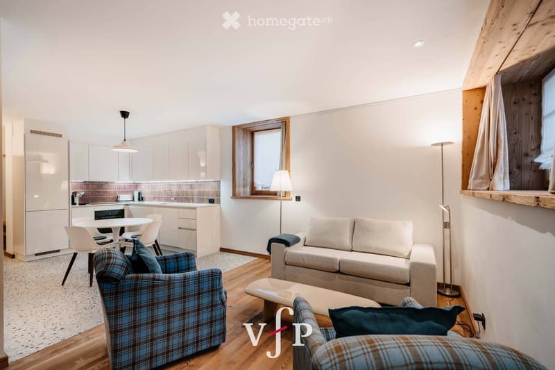 Modern, open-concept living and dining area with a sofa, armchair, coffee table, dining table, and chairs. The kitchen features white cabinets, a refrigerator, and an oven. The space includes wooden flooring, large windows, and floor lamps.