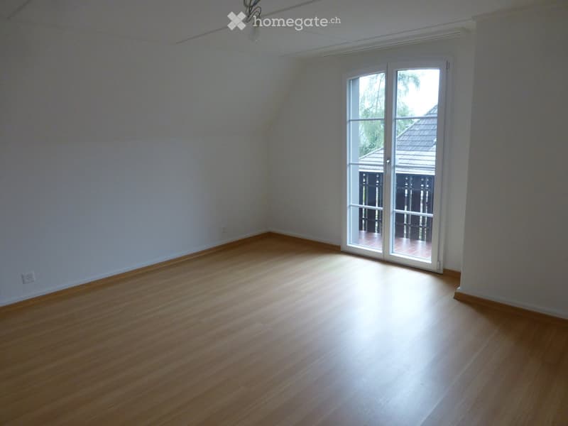 Empty room with wooden flooring, white walls, and a large sliding glass door leading to an outdoor area.