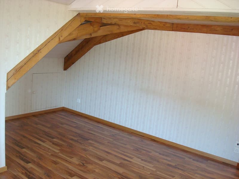 room with wooden floor, sloped ceiling, white walls with stripes, power outlet