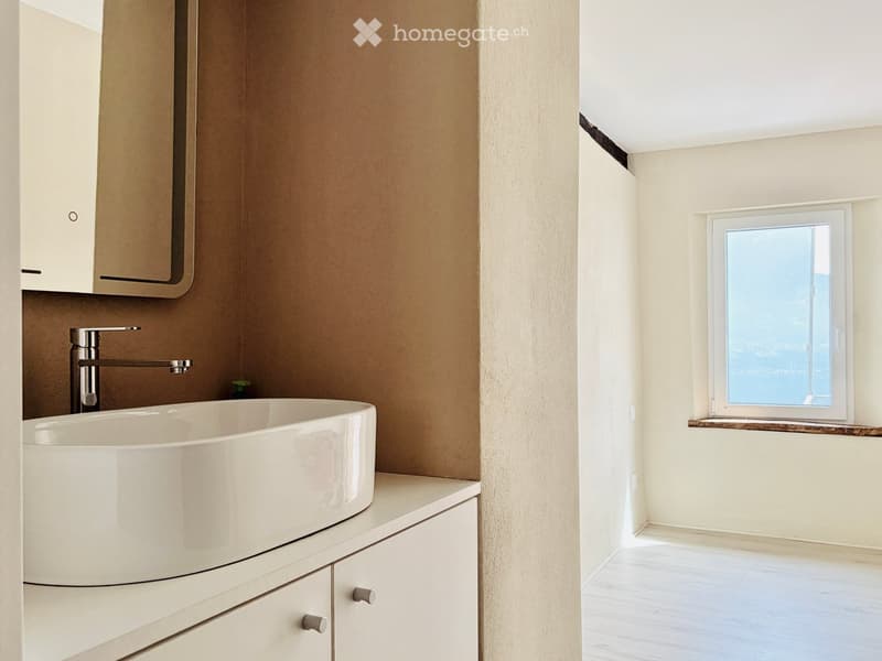 Modern bathroom with a white sink, sleek faucet, and built-in cabinets. A window offers a scenic view.