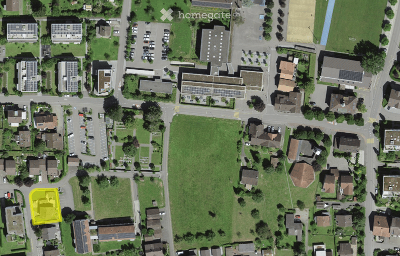 Aerial view of a residential area with multiple houses, parking lots, and green spaces.