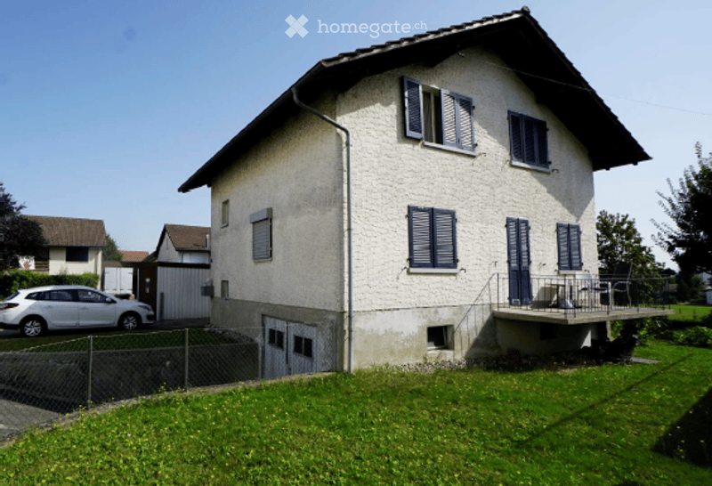 Two-story house with white exterior, blue shutters, and a small balcony on the upper level.