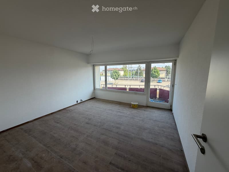 Empty room with tiled floor, white walls, large windows, and a sliding glass door leading to an outdoor area.