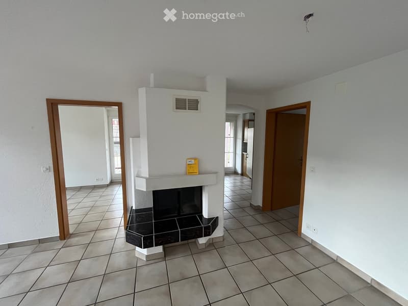 Empty hallway with tiled flooring, white walls, and a fireplace in the center.