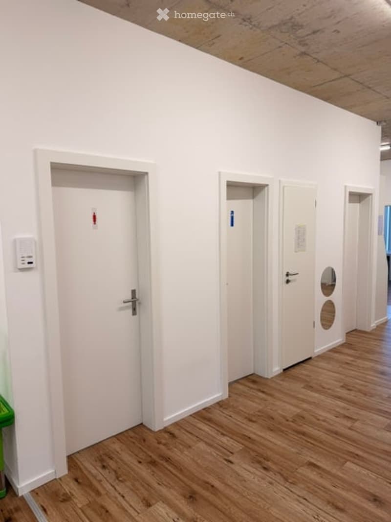Empty room with white walls, wooden flooring, and multiple white doors.