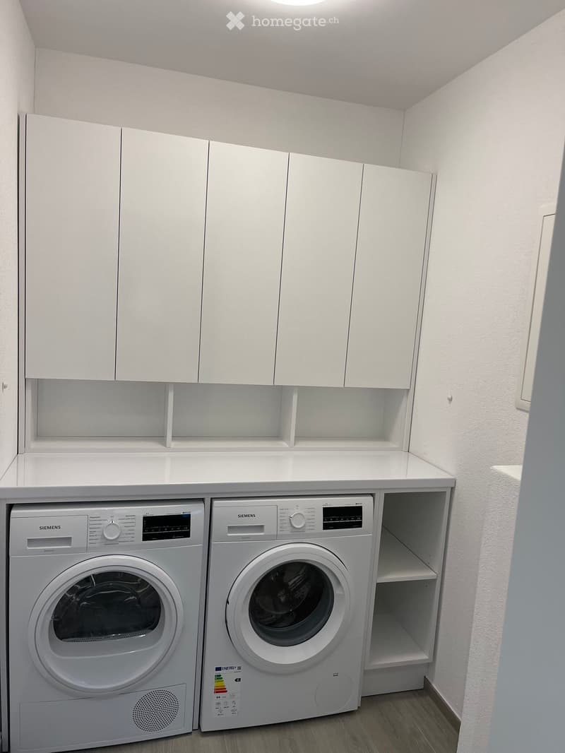 A compact bathroom with white cabinets, a washing machine, and a dishwasher, featuring a sleek and modern design.
