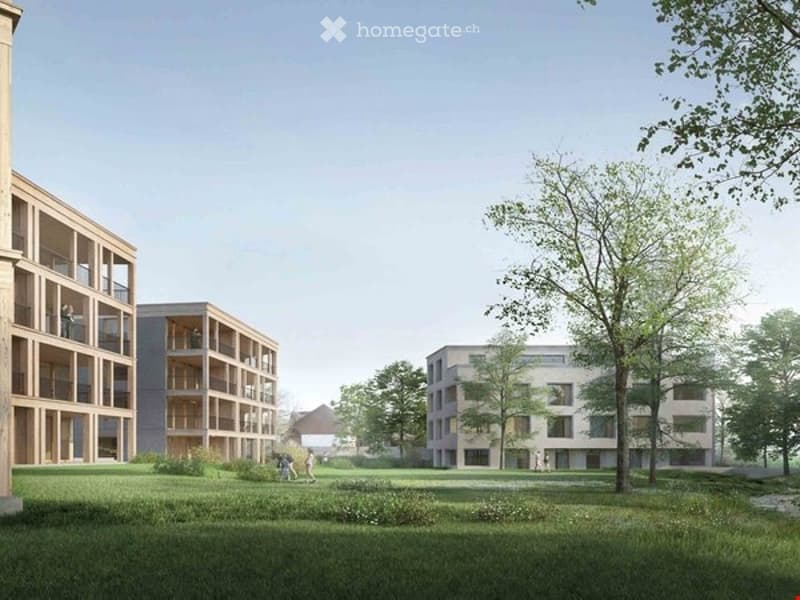 A modern residential complex with multiple apartment buildings, balconies, and a spacious green lawn area.