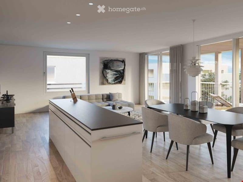 Modern, open-plan living and dining area with a white kitchen island, grey sofa, dining table with chairs, and large windows leading to a balcony.