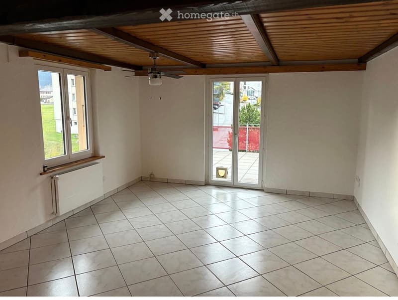 Empty room with tiled floor, white walls, large window, sliding glass door leading to a balcony, and a ceiling fan.