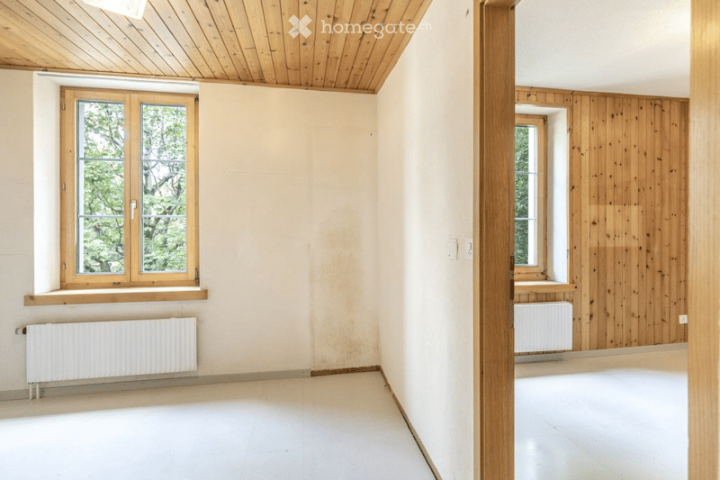 Empty room with wooden ceiling, white walls, large windows, and radiators. No furniture or equipment present.