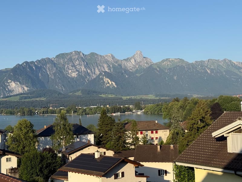 Scenic view of a town with houses, surrounded by a lake and mountain range in the background.