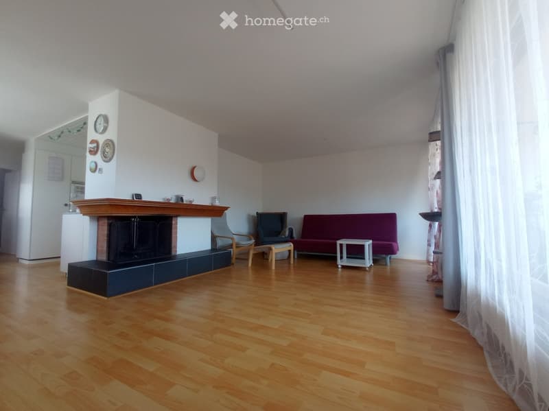 Living room with wooden flooring, fireplace, sofa, chairs, and a small table.