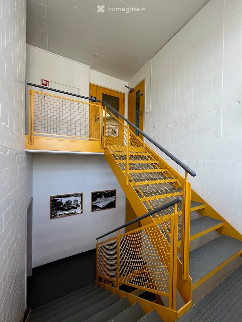 yellow staircase with gray handrails, two picture frames on the wall