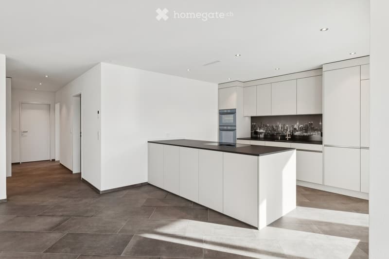 Modern kitchen with island counter, tiled flooring, white cabinetry, black countertops, integrated appliances, large windows